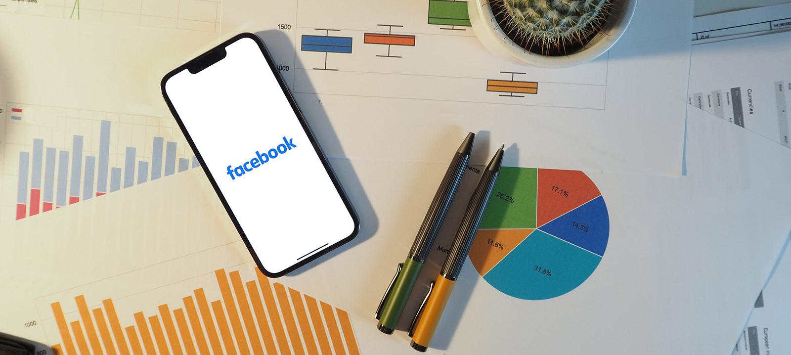 Cell phone on the desk with Facebook application open Cell phone on the desk with Facebook application open